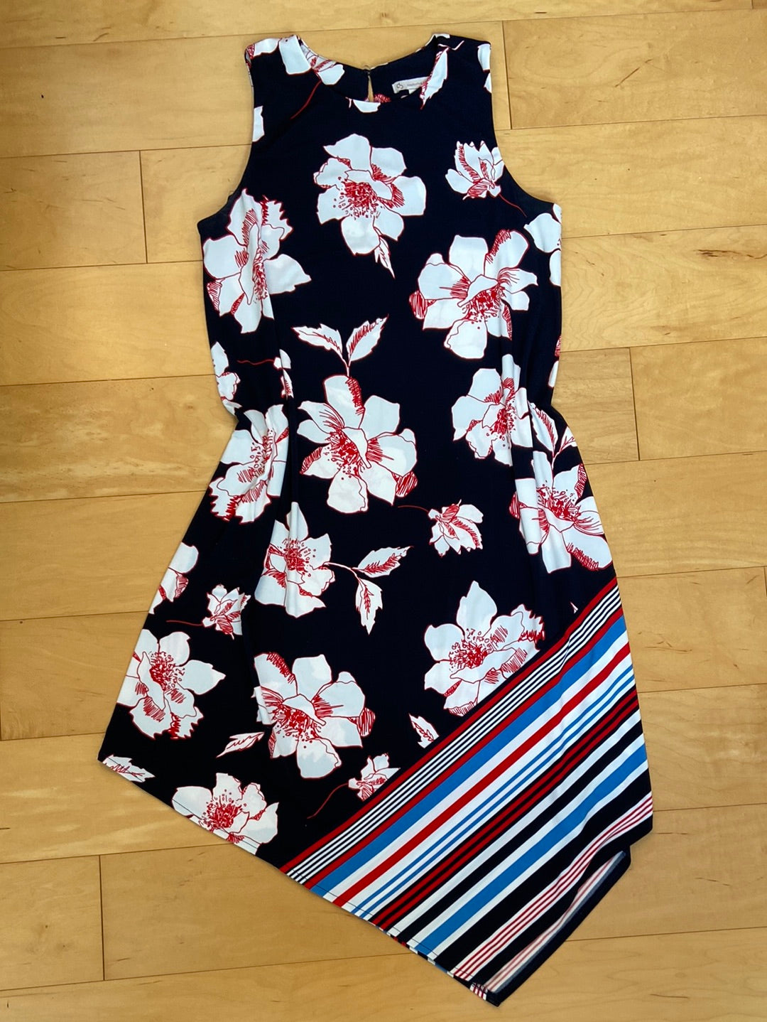 Black dress sleeveless asymmetrical hem with stripes on the bottom and floral print on top white flowers with red trim stripes are blue red and white